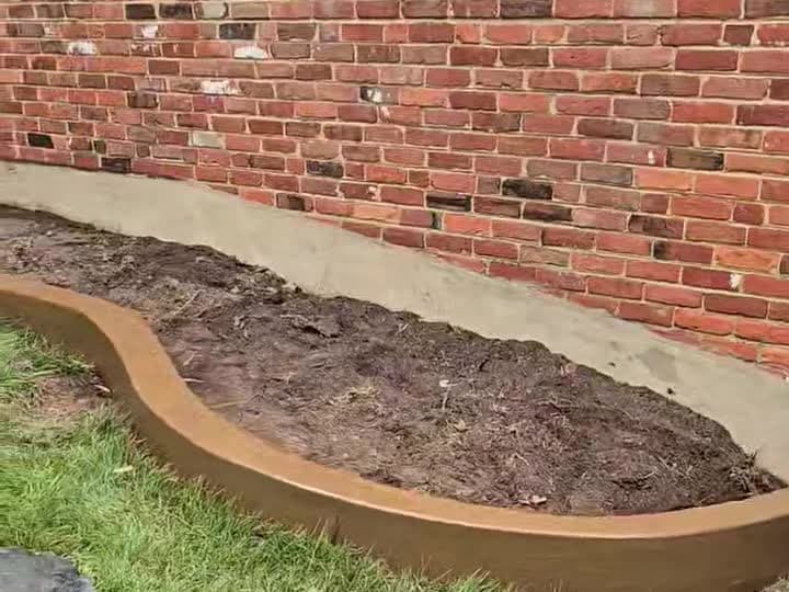 Finished curved colored concrete landscape curbing around a planting bed in Oakton, VA